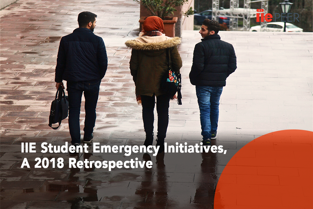 Three students in a row walking away from the camera outside